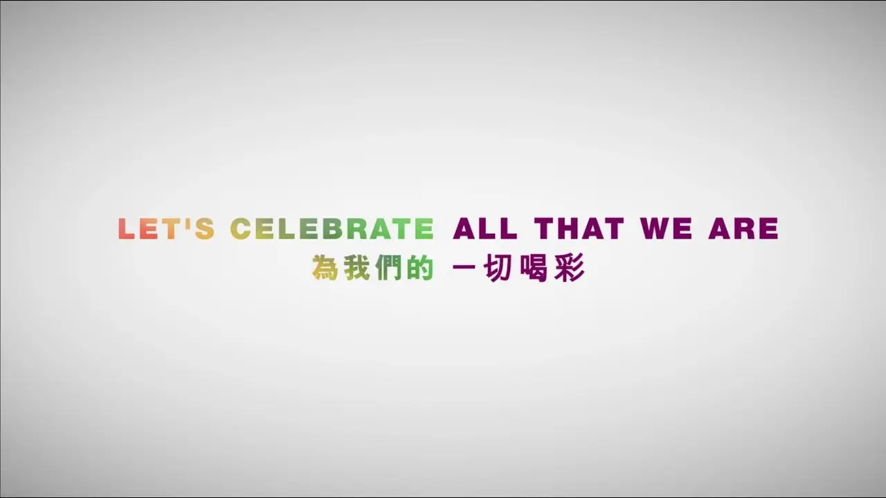 Image with the text "LET'S CELEBRATE ALL THAT WE ARE" in multicolored letters in English, followed by a Chinese translation "為我們的一切喝彩" in green text, on a light grey background. Ideal for use in a promotional video by a video production house.