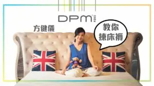 A person sits on a beige tufted sofa with Union Jack pillows on both sides, holding a stuffed animal. The background features colorful lines at the top and Chinese text saying "方健儀" along with a speech bubble that reads "教你撇床褥." The DPM Home logo is displayed above, as part of an exhibition promotion.