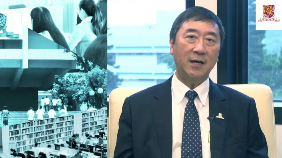 A man in a suit and tie sits in an office setting, speaking. Behind him on the left side, there is a collage of images showing students, a library, and a building. The logo of a university is visible in the top right corner. The scene has elements that could benefit from animation by a professional video production house to enhance its visual appeal.