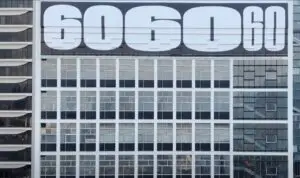 An office building exterior with large numerals "6060" displayed prominently at the top. The building facade showcases a grid of large windows, reflecting the sky and surroundings. Modern architectural design elements make it ideal for promotional video shoots highlighting urban advancements.