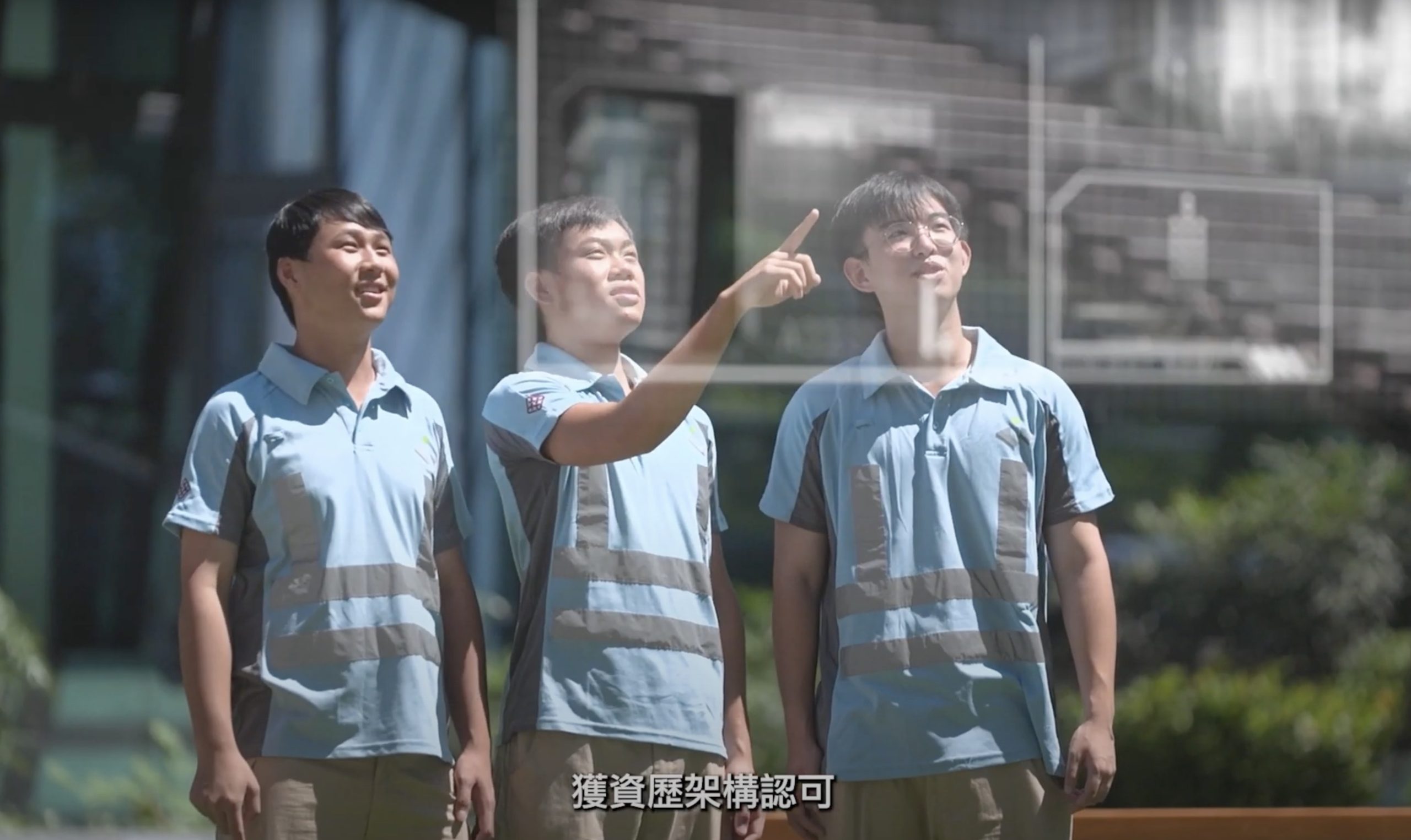 Three men in matching light blue uniforms stand outdoors; one points ahead while the others look in the same direction. Sunlight is bright, and there are buildings and greenery in the background. Chinese subtitles are visible at the bottom.
