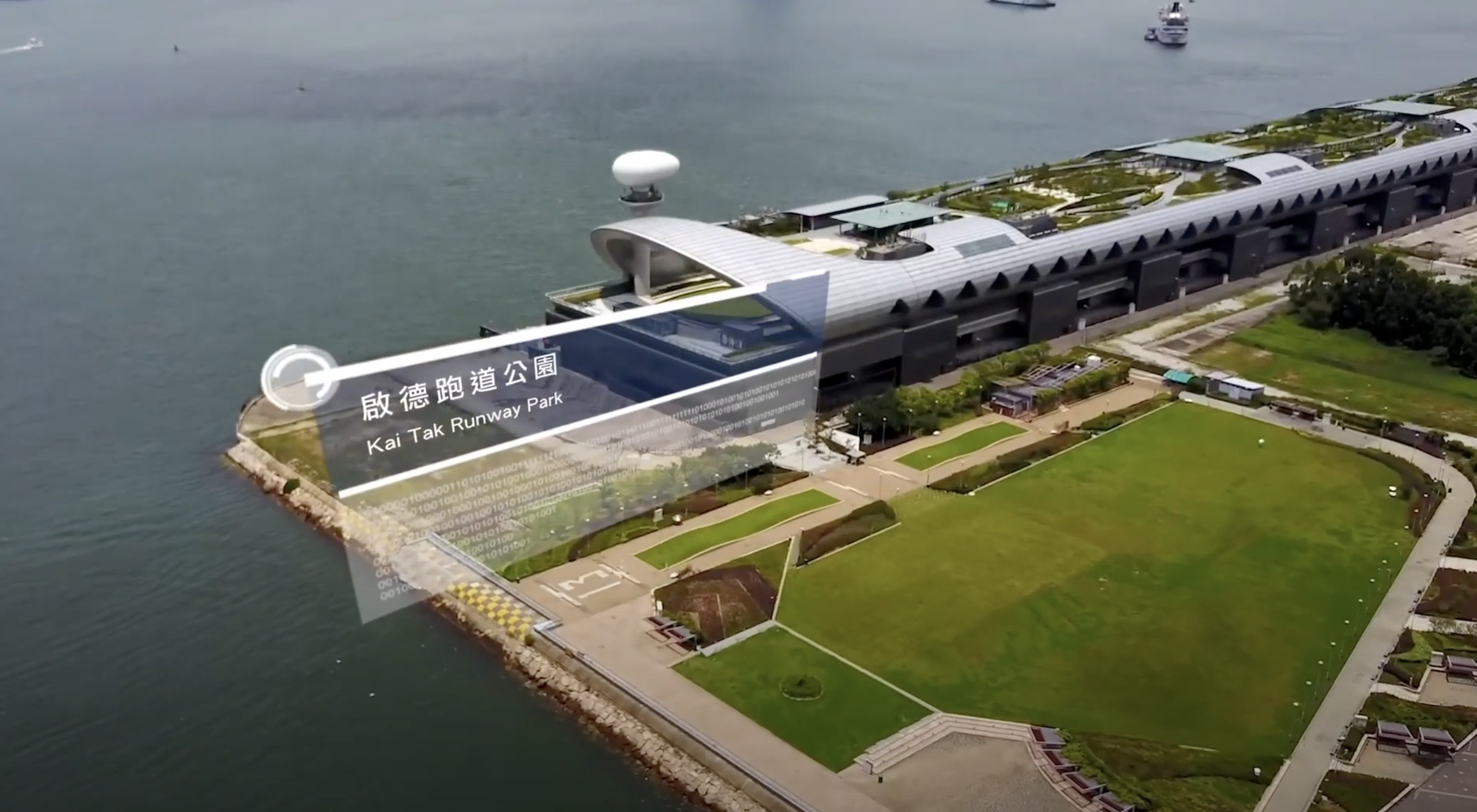 A modern waterfront park with green lawns and walkways extends along the shoreline beside a sleek, futuristic building. Overlaid text labels the location as "Kai Tak Runway Park" in English and Chinese.