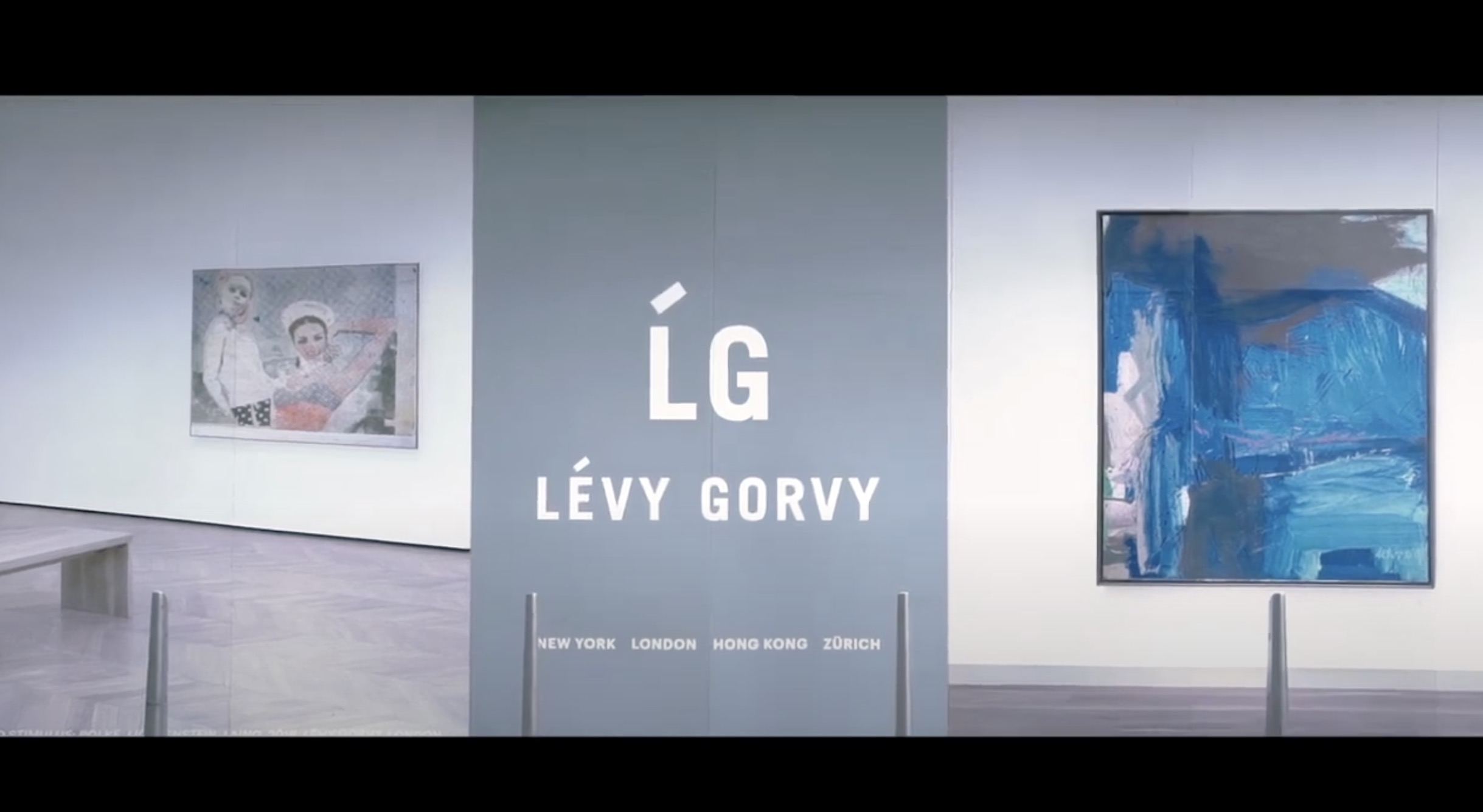 A gallery wall displays the text "LÉVY GORVY" and "LG" with locations listed below. Abstract paintings hang on white walls to the left and right of the sign.