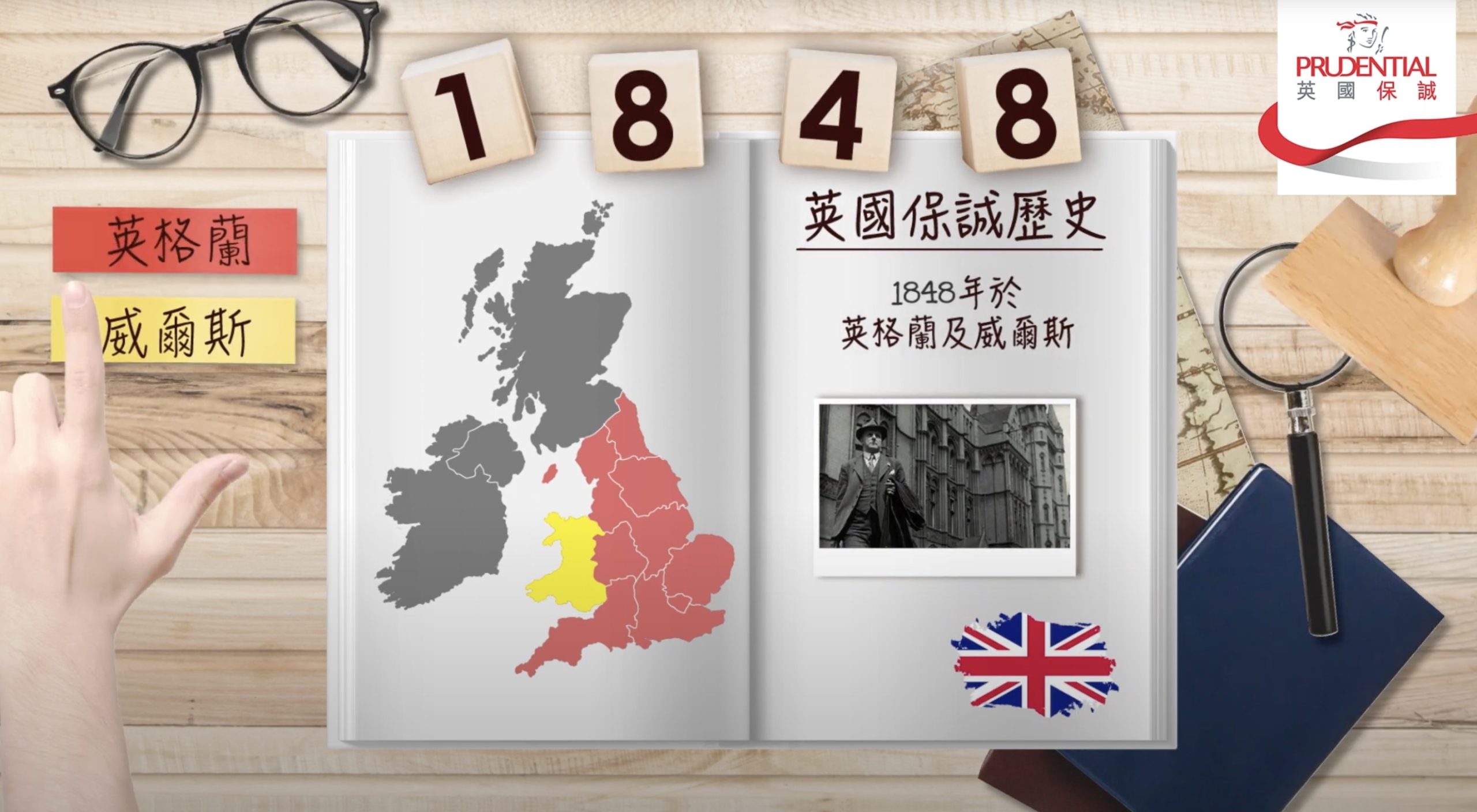 An open book displays a map of Britain with England, Scotland, and Wales highlighted. The year 1848 and Chinese text are present. A hand points to tags, and the Prudential logo appears in the top right corner.