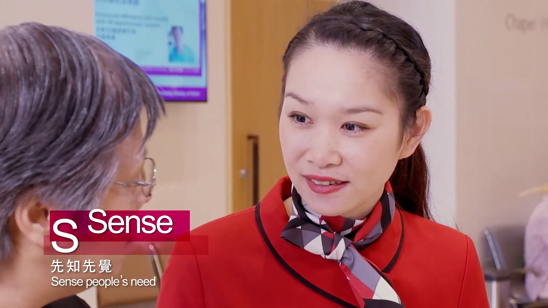 A woman in a red uniform with a patterned scarf speaks to an older person with gray hair. The word "Sense" and text in Chinese and English appear on the image. A blurred sign and wooden door are in the background.
