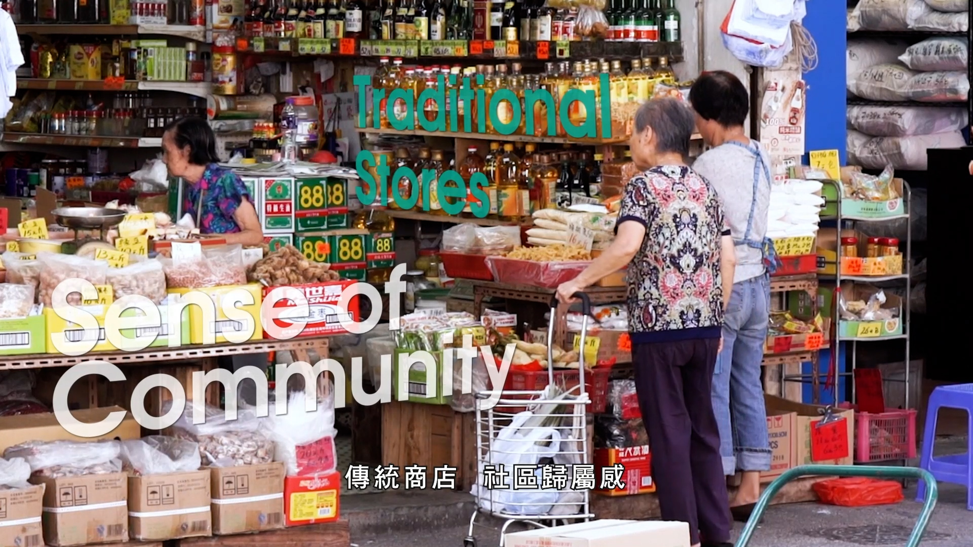 Two elderly women shop at a traditional Asian market stall selling groceries and dry goods. Colorful signs, stacked products, and handwritten prices are visible. Text reads “Traditional Stores, Sense of Community” in English and Chinese.