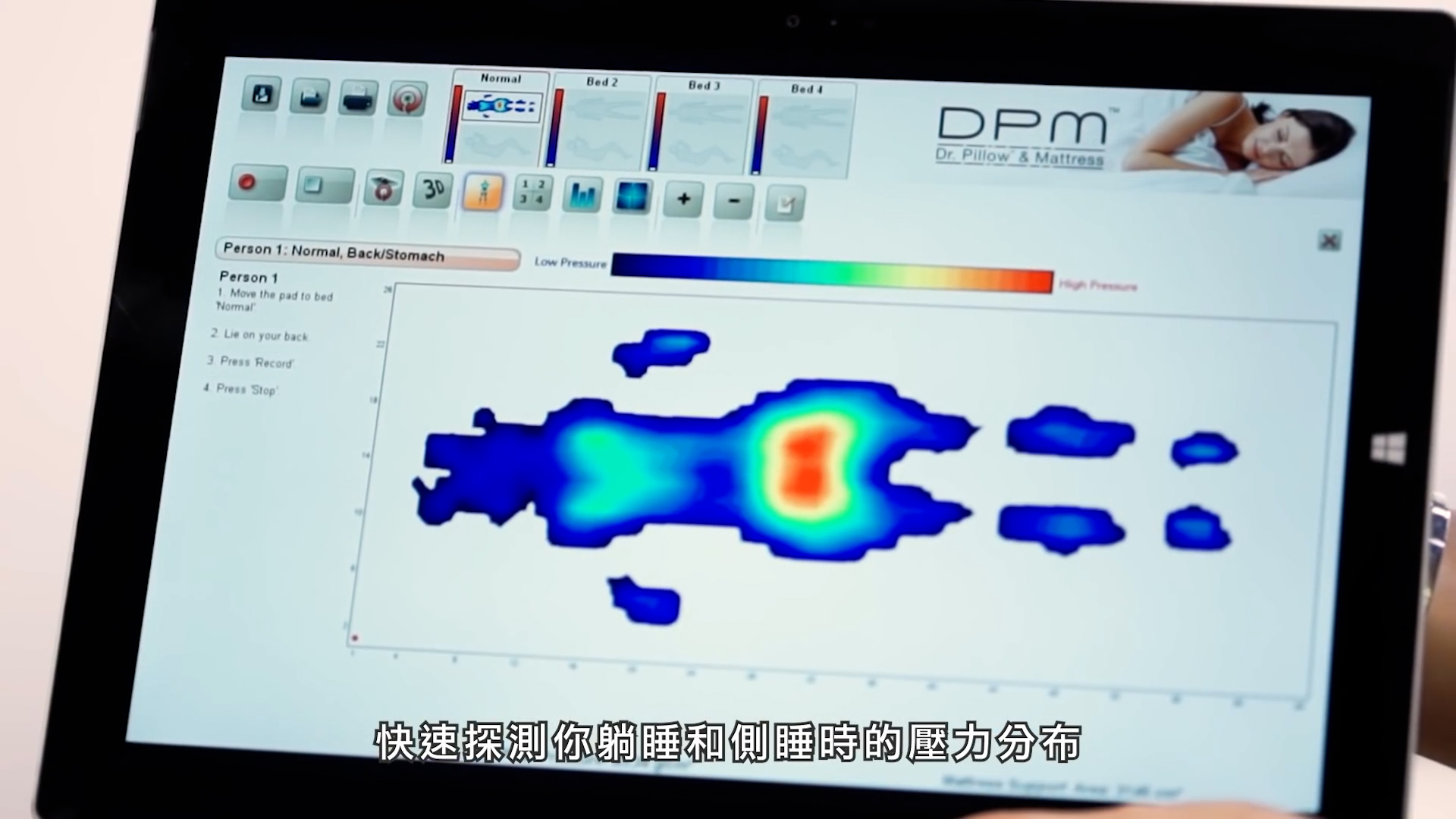 A tablet displays a heat map indicating pressure distribution on a mattress for different sleeping positions, with Chinese subtitles at the bottom and interface buttons at the top.