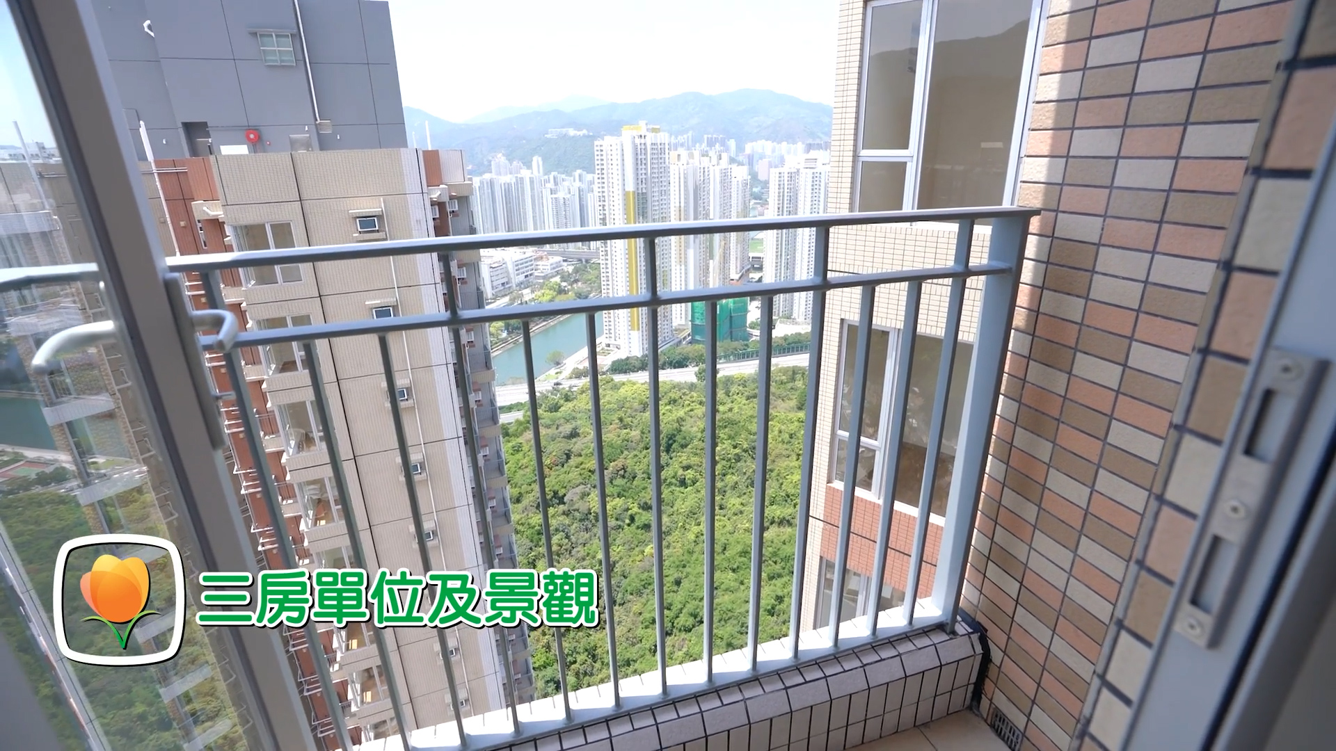 A balcony with a metal railing overlooks a cityscape with tall apartment buildings and greenery. Chinese text and a flower icon are displayed in the bottom left corner.