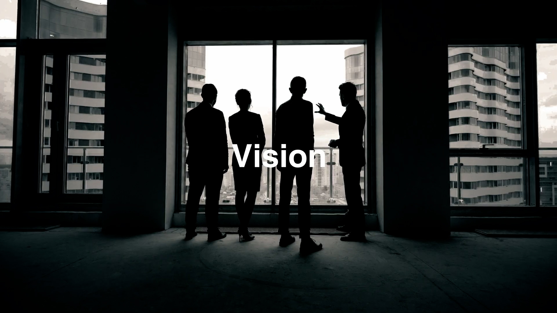 Silhouettes of four people standing in front of a large window overlooking city buildings, with the word "Vision" displayed in bold white text across the center.