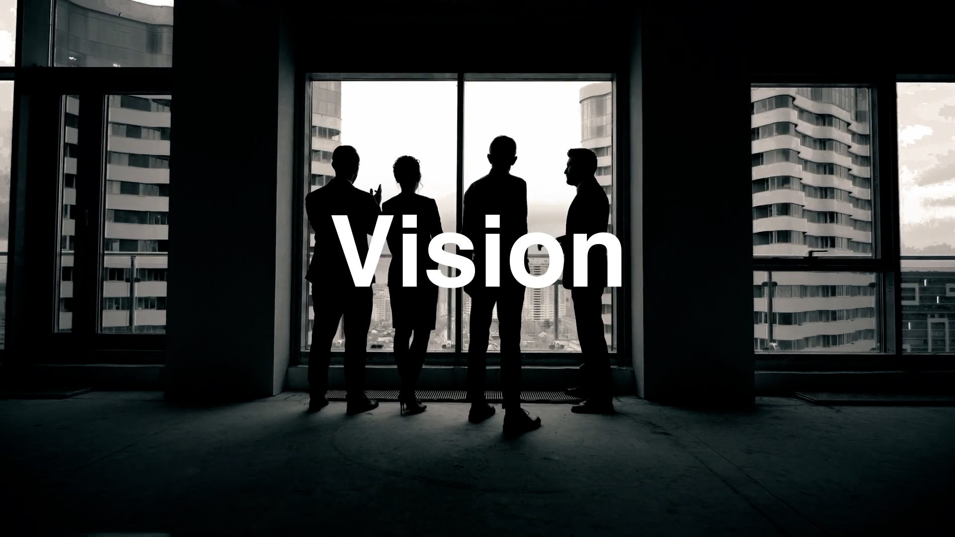 Four people are silhouetted as they stand in front of large windows in a modern building, with the word "Vision" in bold white text centered over the image.