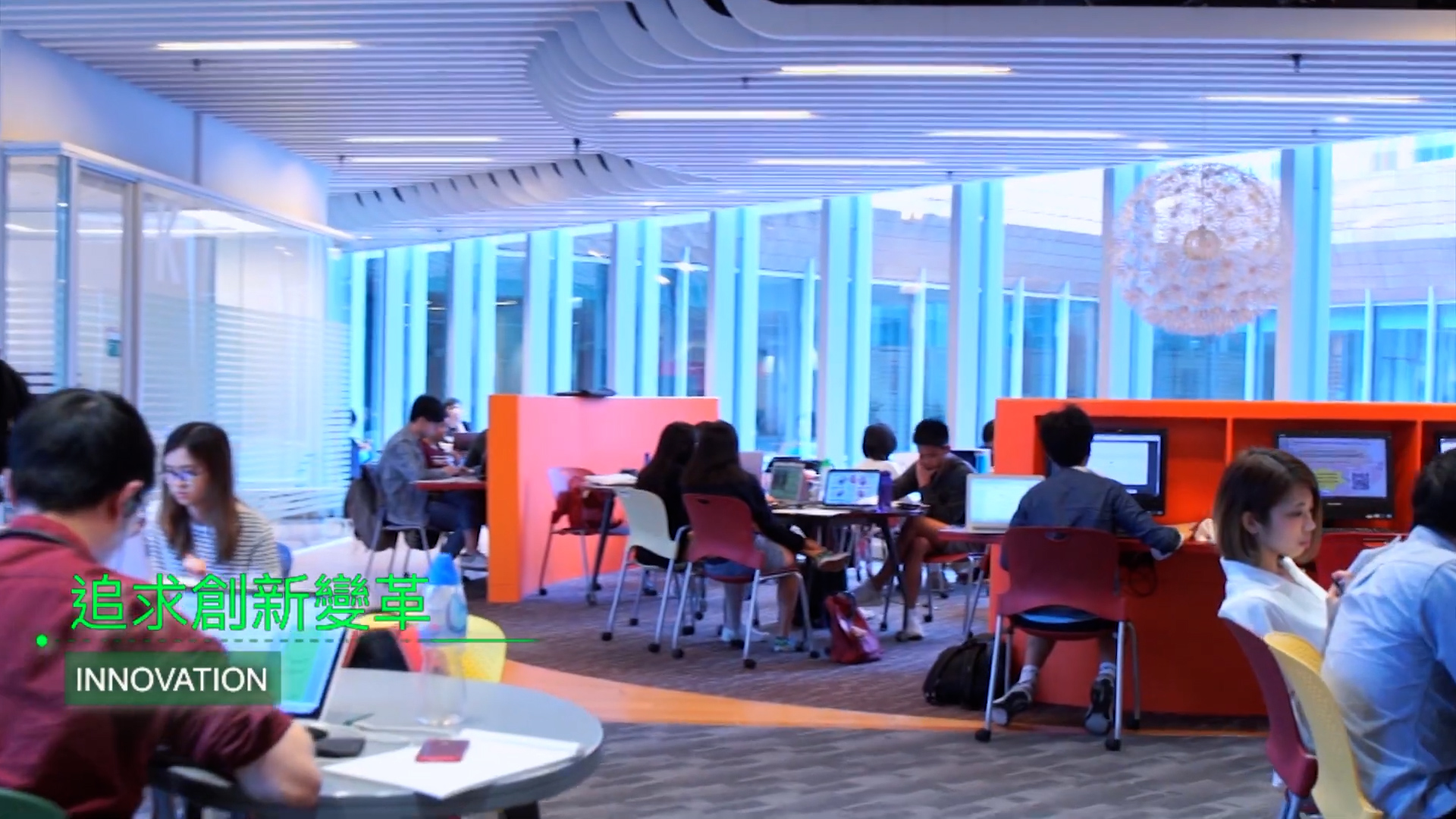 Students work and study in a modern, colorful library space with large windows and bright orange seating areas. The Chinese text reads “追求創新變革” and below it is the English word “INNOVATION.”.