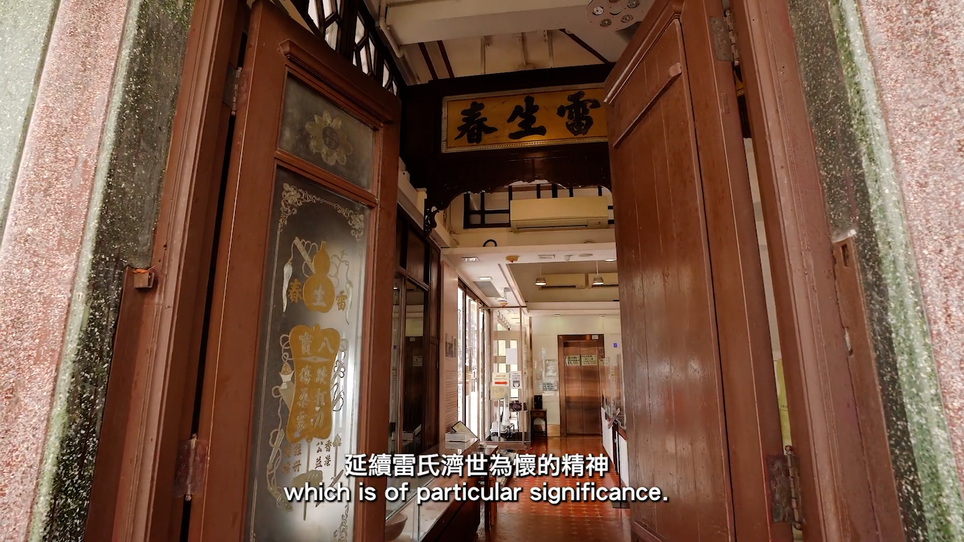 An ornate wooden doorway opens into a traditional Chinese interior with glass panels, decorative carvings, and hanging signs. English and Chinese subtitles read, "which is of particular significance.