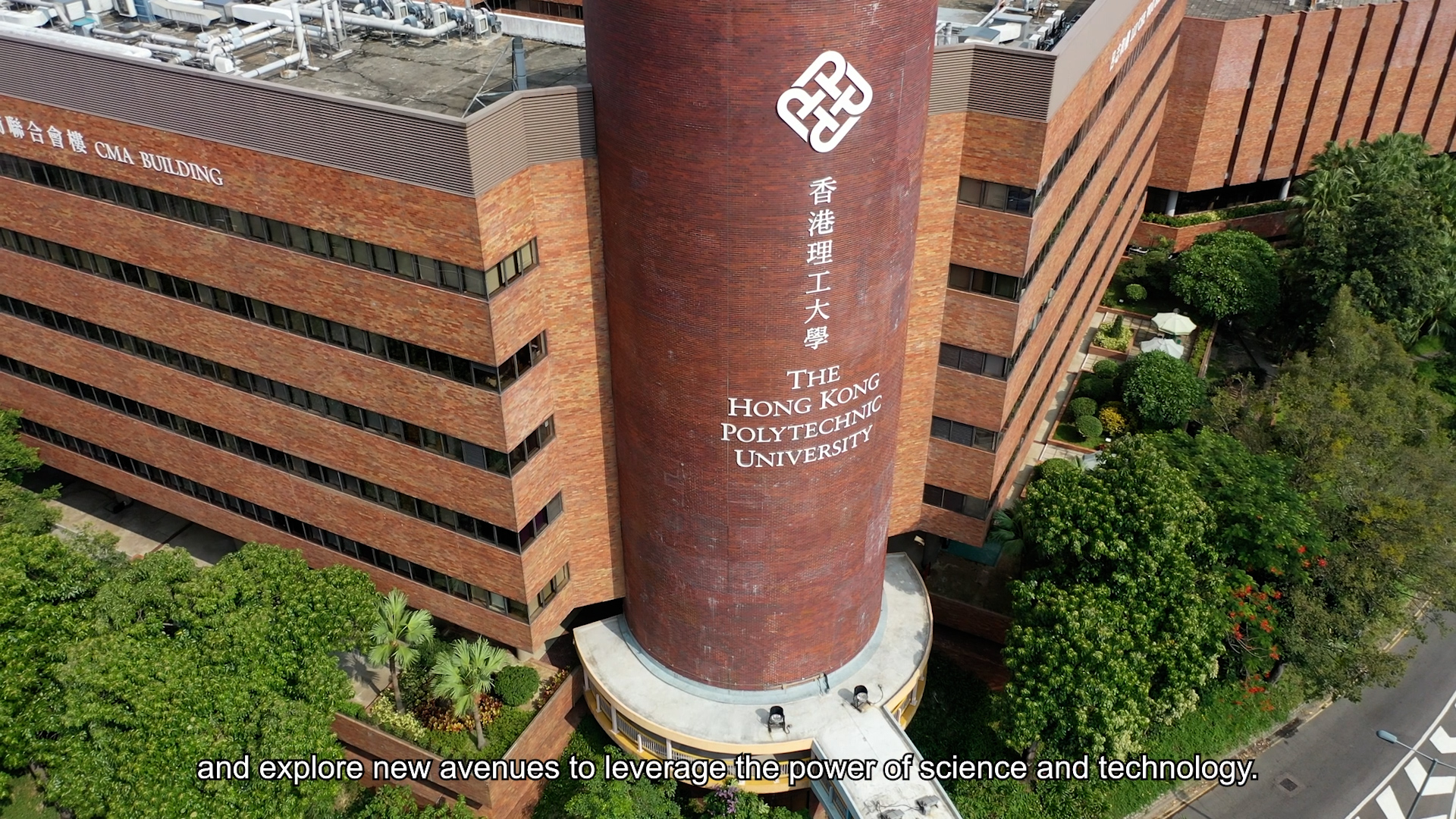 Aerial view of the main building at The Hong Kong Polytechnic University, featuring its distinctive cylindrical tower with the university's name, surrounded by trees. Subtitles read: "and explore new avenues to leverage the power of science and technology.