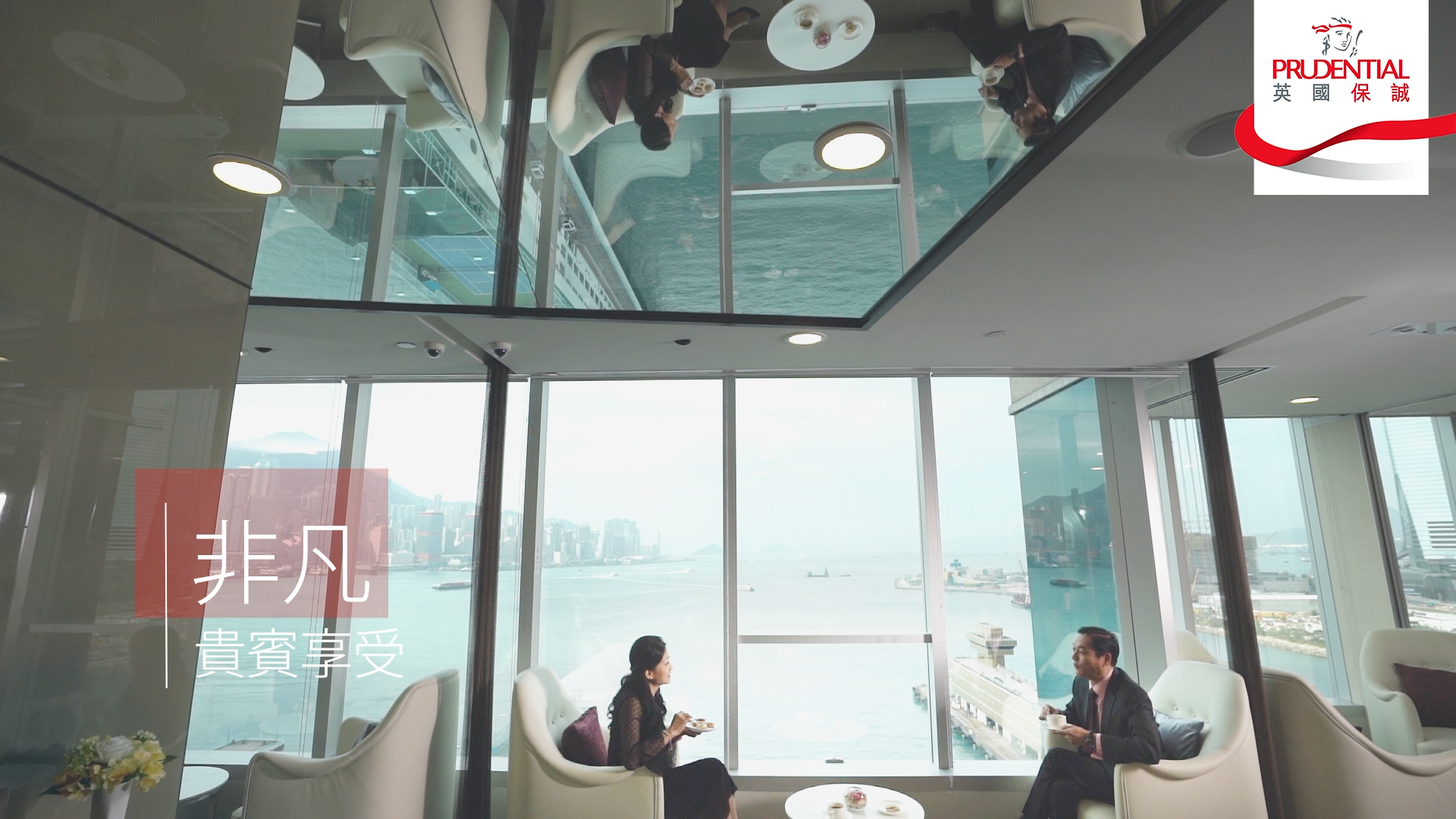 Two people sit across from each other at a small table by large windows overlooking a harbor, with their reflections visible on the ceiling. The Prudential logo is in the top right corner, and Chinese text is on the left side.