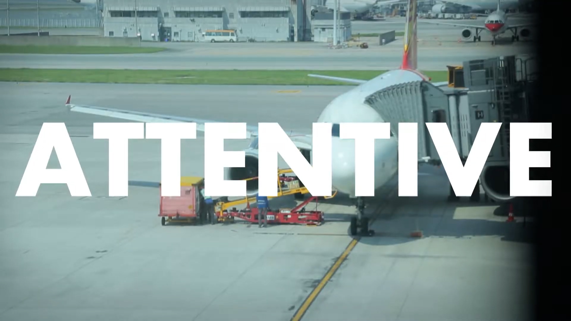 A commercial airplane is parked at an airport gate with ground service vehicles nearby. The large word "ATTENTIVE" is overlaid in bold white letters across the center of the image.