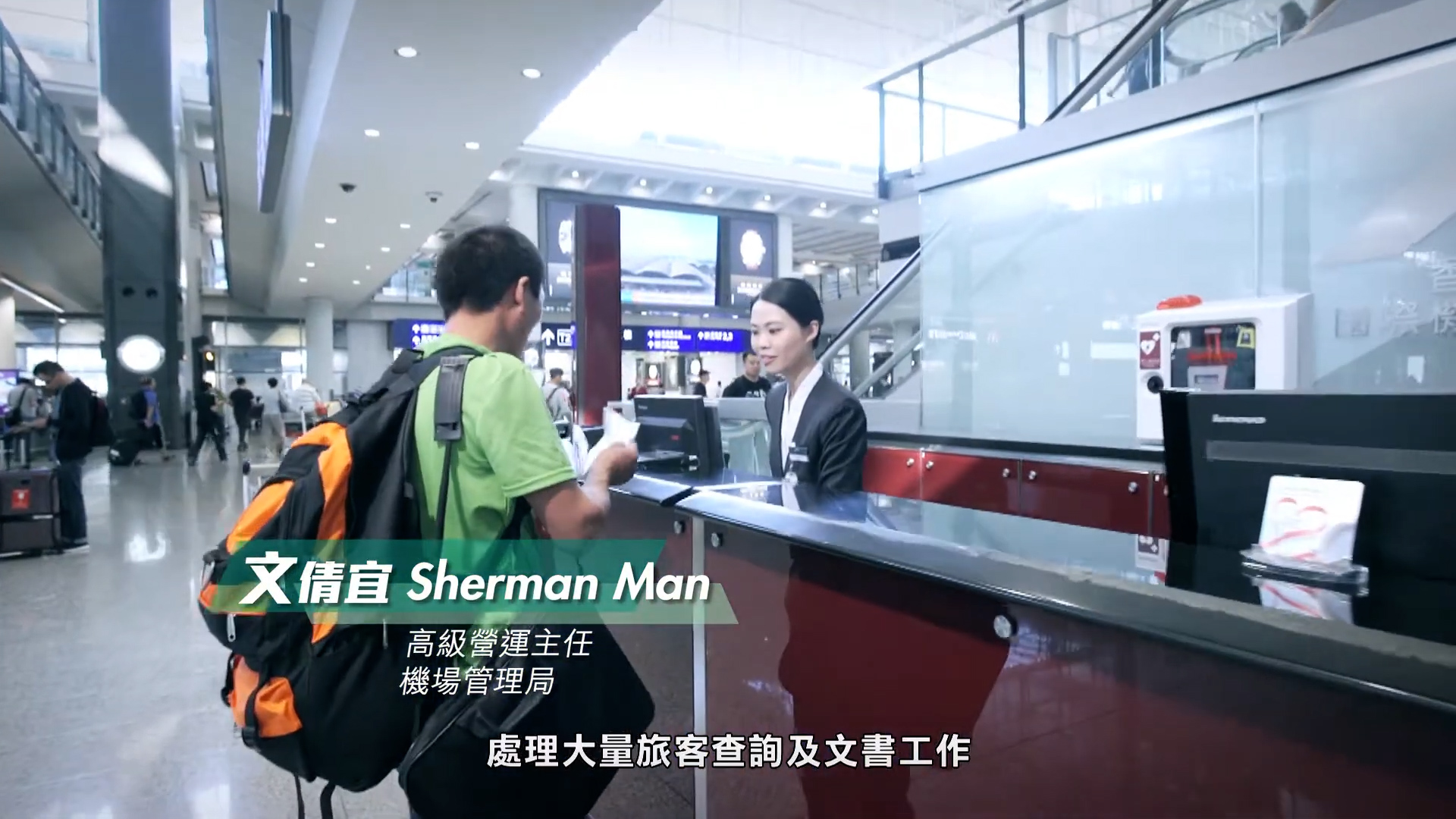 A traveler with an orange and green backpack speaks to a female staff member at an information counter in a busy airport terminal. Chinese and English subtitles identify the staff member as Sherman Man.